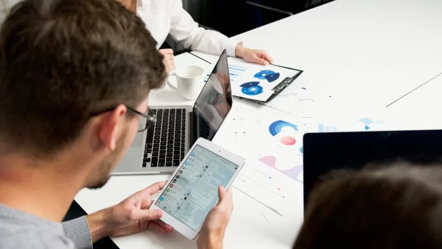 Colleagues collaborating on a B2B Project Management dashboard and financial data analysis.