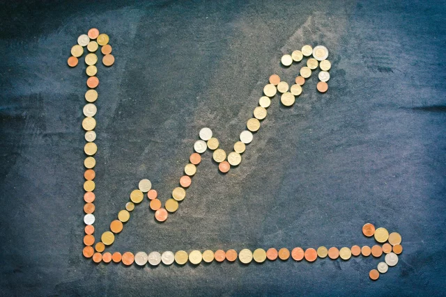Coins arranged on a dark surface to form a line graph demonstrating growth for Project Management in Banking.