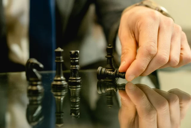 A hand in a suit moves a chess piece to symbolize strategic decision-making in a PMO environment.