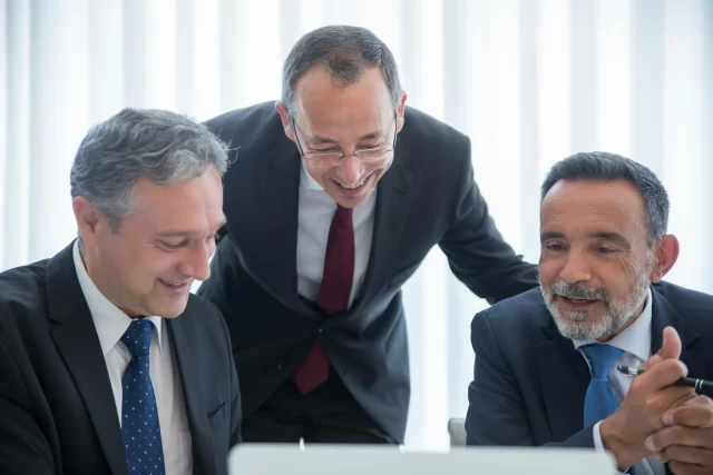 Three professionals collaborating on a strategy during a PMO meeting.