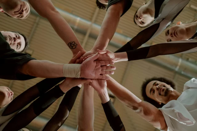 A team of diverse individuals stacking their hands together in a circle, representing Collaboration in Project Management.