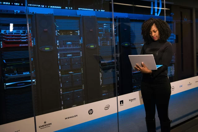 A technician reviews a digital Task Breakdown while monitoring servers in a modern data center.