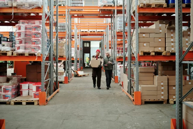Two workers inspecting inventory in a warehouse to ensure effective Supply and Chain Management.