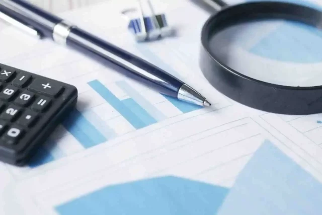 Pen, calculator, and magnifying glass resting on a chart, illustrating the analytical process for NORSTRAT.