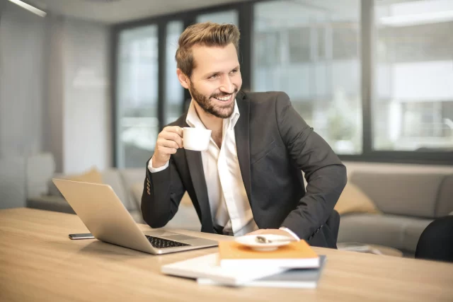 Professional at a desk with a laptop, reflecting on Swiss supply and chain management strategy.