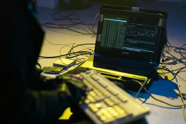 A hacker working on a laptop, using tools to streamline technical manager project management tasks.