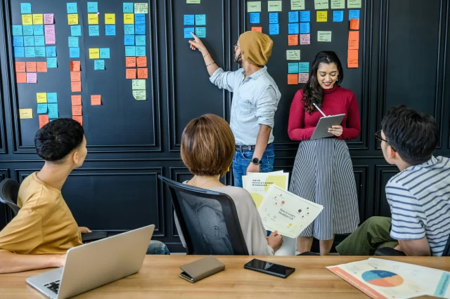 Diverse team collaborating on a strategy wall to optimize their manager project management workflows.