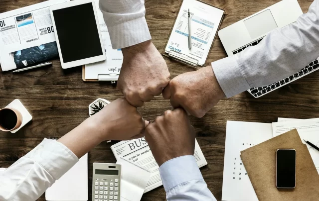 Business professionals fist-bumping over a desk to prevent a portfolio at risk in Zürich.