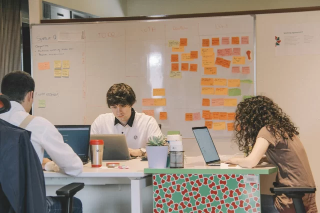 Three professionals collaborating in an office setting to implement Agile in Switzerland methodologies.