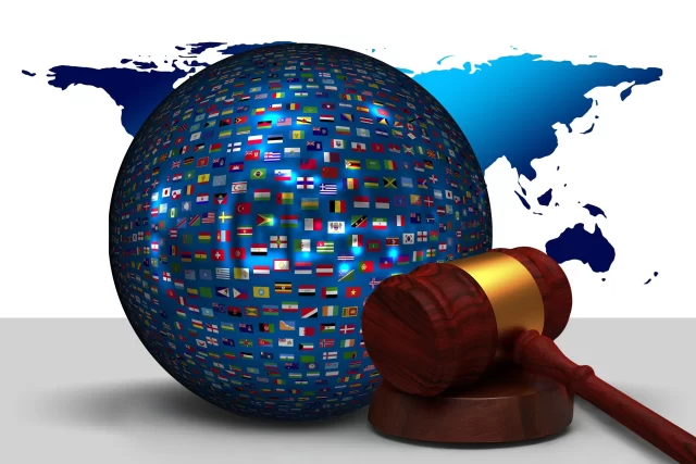 A judge's gavel beside a globe covered in international flags, illustrating the global context of Agile in Switzerland.
