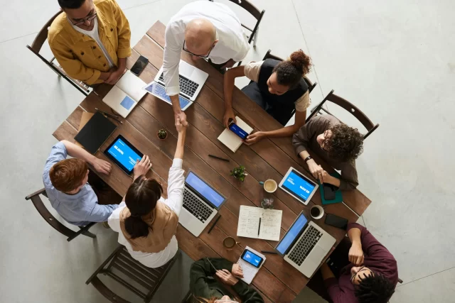 A diverse professional team collaborating around a table while utilizing Swiss ICE CRM software.