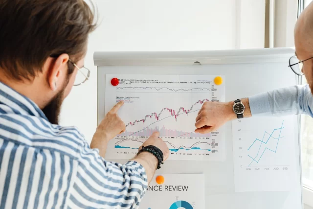 Two business professionals analyzing a financial chart to discuss supply chain management in Switzerland.